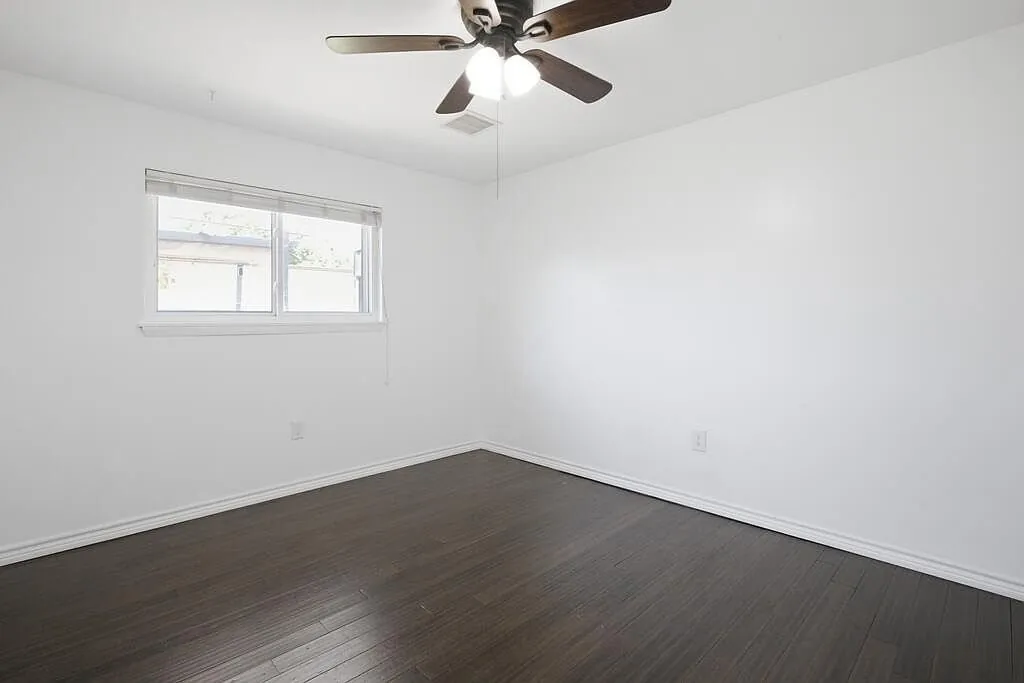 Bedroom after the remodel, with new flooring, fresh paint, and a ceiling fan