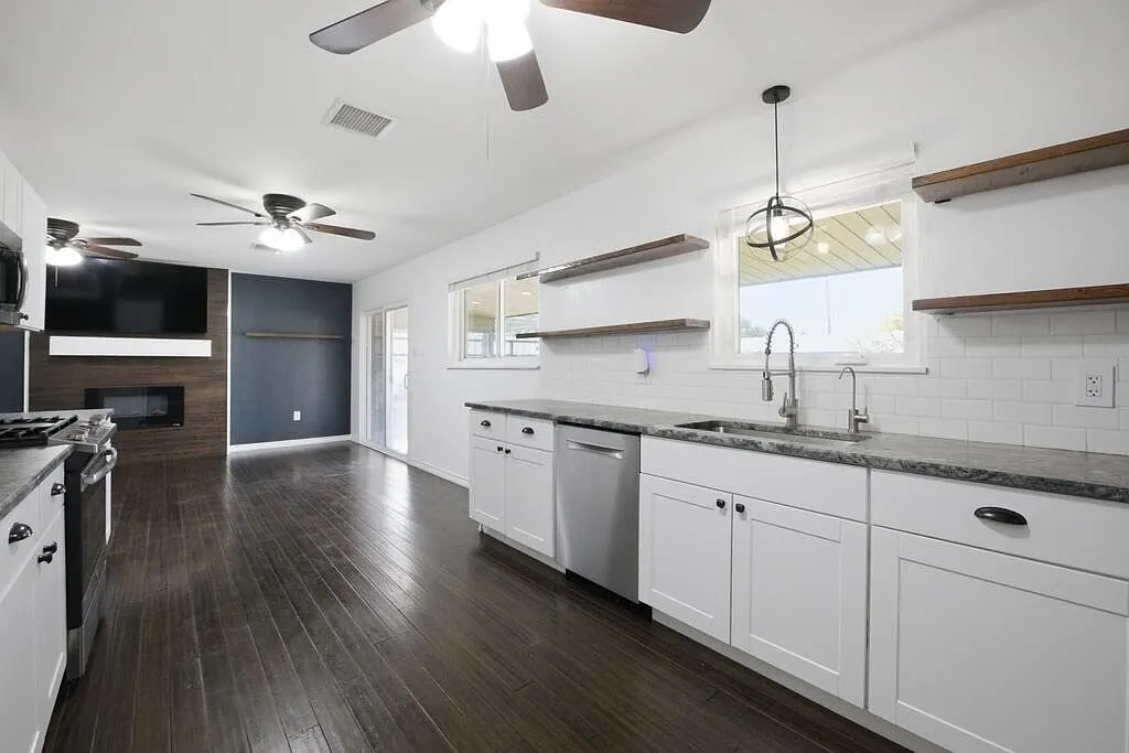Kitchen after the remodel, with white shaker cabinets, granite countertops, and stainless appliances