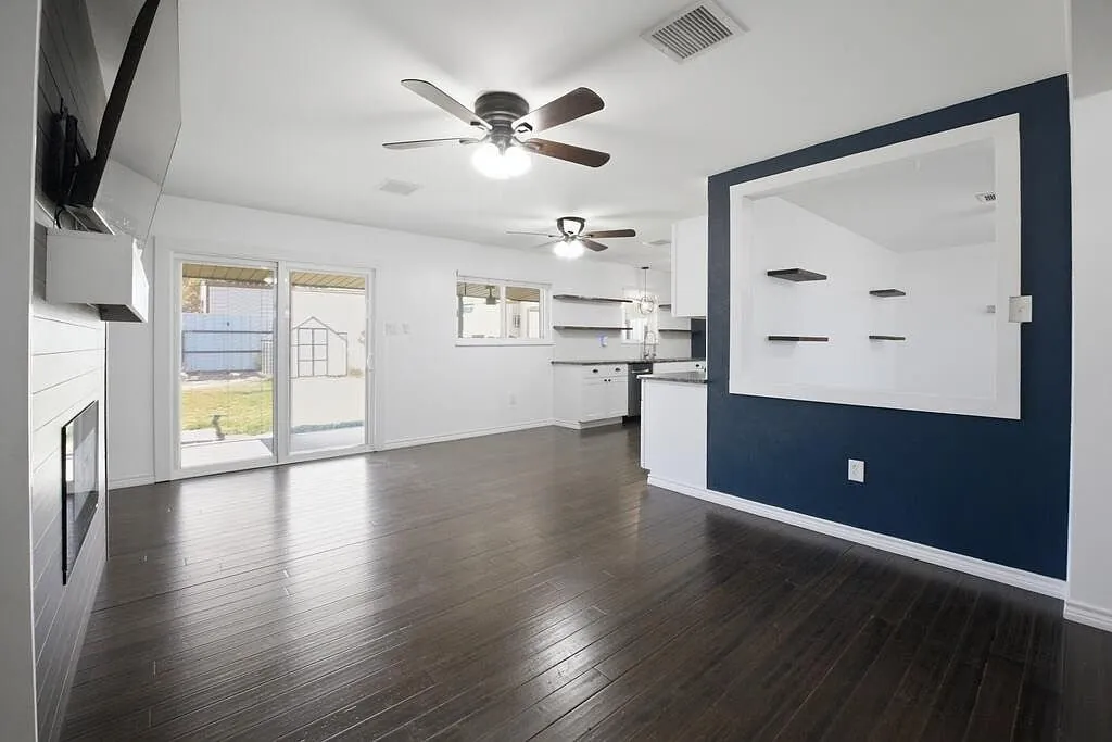 Living room after the remodel, with wood-look flooring, white walls, and a navy accent wall